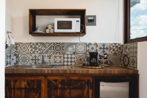 a kitchen counter with a microwave and a cupboard at Villas Palmar Holbox in Holbox Island