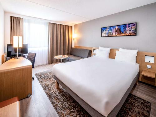a hotel room with a large bed and a couch at Novotel Rotterdam - Schiedam in Schiedam