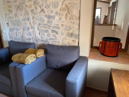 a blue couch in a room with a stone wall at CAL PUIG, ENOTURISMO RURAL entre Viñas y Bosques in Juncosa