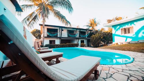 a swimming pool with a hammock next to a house at Surfcamp Arara in Pipa