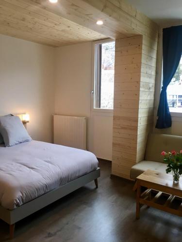 a bedroom with a bed and a window and a table at Studio des Eterlous in Saint-Chaffrey