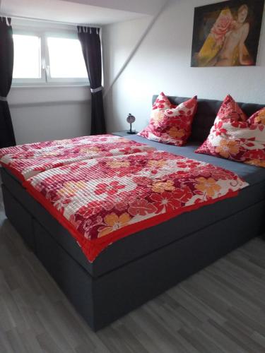 sypialnia z łóżkiem z czerwonym kocem i poduszkami w obiekcie Ferienwohnung Mabo w mieście Kempen