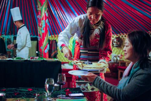 une femme tenant une assiette de nourriture dans une tente dans l'établissement Banyan Tree Ringha, à Shangri-La