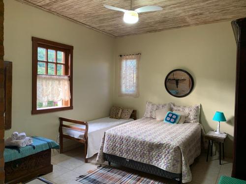 um quarto com uma cama, uma cadeira e uma janela em Pouso Flor de Manacá em Tiradentes