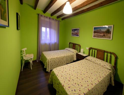 a room with two beds and green walls at El Chorrón in El Royo