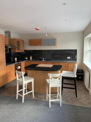 a kitchen with two white chairs and a table at The Plaza Suites High St Bangor in Bangor