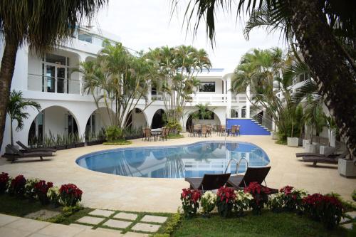 a hotel with a swimming pool and palm trees at Hotel Gran Costa Azul in Puerto Santo Tomás de Castilla