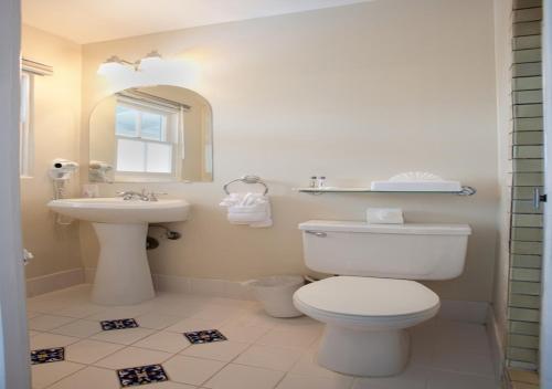 a white bathroom with a toilet and a sink at Coast Village Inn in Santa Barbara
