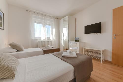a white bedroom with two beds and a television at Villa Cera in Pula