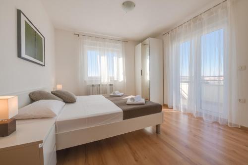 a white bedroom with a large bed and large windows at Villa Cera in Pula