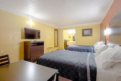 a hotel room with two beds and a flat screen tv at Economy Inn & Suites in Denton