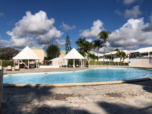 圣弗朗索瓦LES MARINES KAZATIBO的一座带白色帐篷和棕榈树的大型游泳池