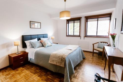 a bedroom with a bed and a desk and windows at Castle Apartment in Guimarães