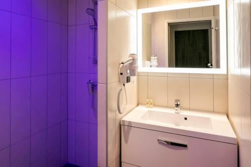 a purple bathroom with a sink and a mirror at Hotel Du Commerce Spa in Saint-Gaudens