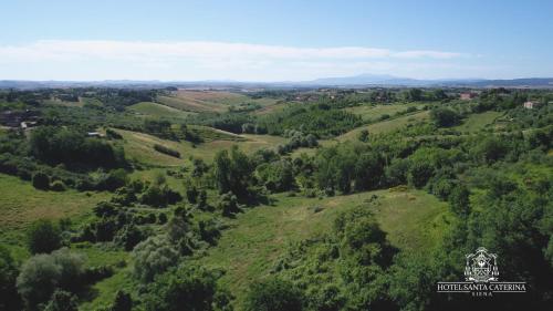an aerial view of a green hill with a building on it at Hotel Santa Caterina in Siena