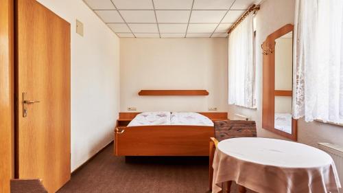 a small room with a bed and a table at Pension Grenzhof in Neuhausen