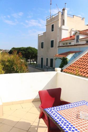 a red chair sitting on a balcony with a table at Casa Londres in Estoril