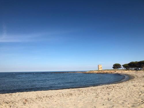 a sandy beach with a lighthouse in the distance at B&B Levante Posada in Posada