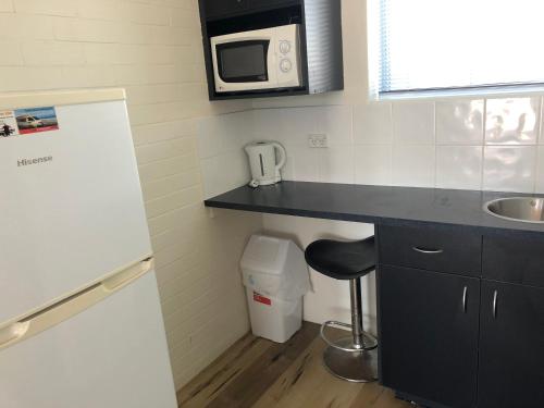 a small kitchen with a sink and a microwave at Hervey Bay Motel in Hervey Bay