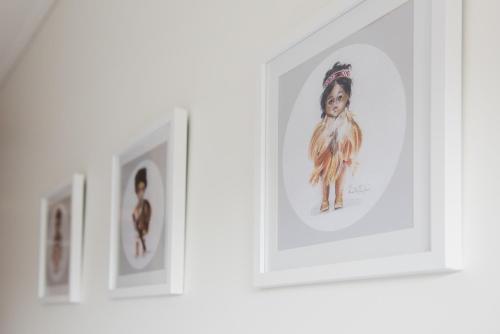 a row of framed photographs on a wall at The Lodges At Transport World in Invercargill