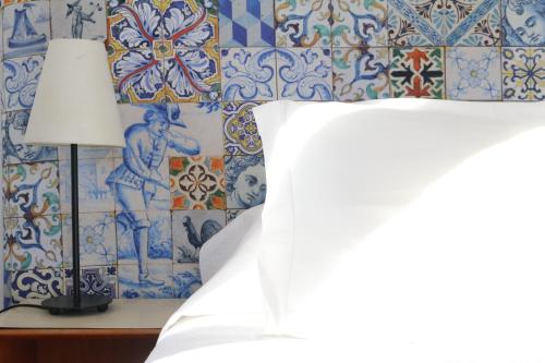a bedroom with a bed and a wall with blue and white tiles at Casa Londres in Estoril