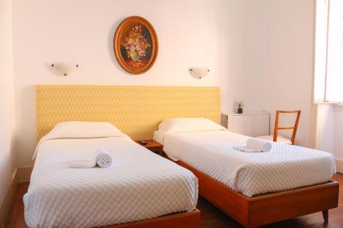 a bedroom with two beds and a clock on the wall at Casa Londres in Estoril