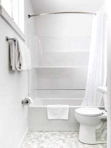 a white bathroom with a toilet and a shower at The Nomad Motel - International Falls, MN - Near Canadian Border in International Falls