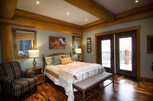 a bedroom with a bed and a chair and windows at Golden Acres Mountain Lodge in Golden