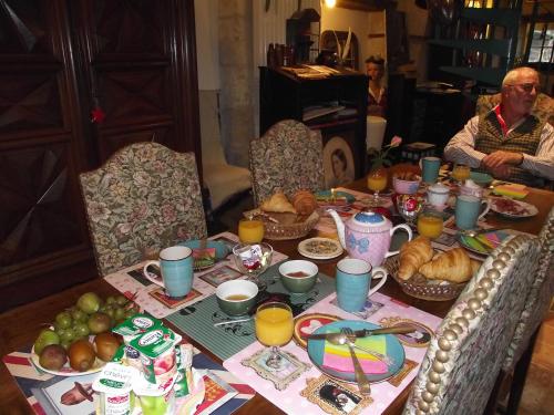 Chambre d'hôtes Le Vaujoint في Cheillé: يجلس رجل على طاولة مع الطعام وعصير البرتقال