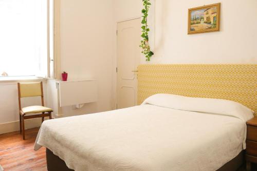 a bedroom with a bed and a chair and a window at Casa Londres in Estoril