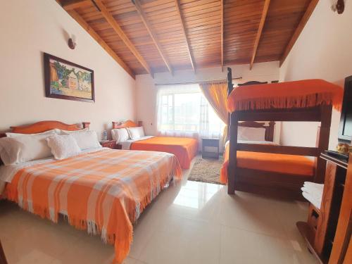 een slaapkamer met 2 bedden en een groot raam bij Hotel Quinta de Santa Ana in Tibasosa
