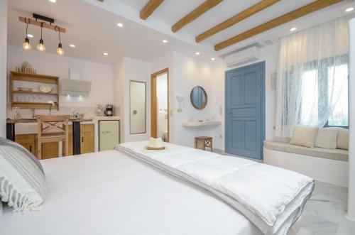 a bedroom with a large white bed and a kitchen at Asterias Studios in Agia Anna Naxos