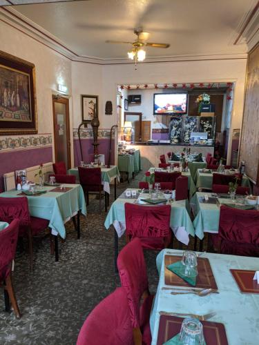 a restaurant with tables and chairs and a television at The New Guilderoy Hotel in Blackpool