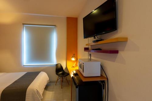 a bedroom with a bed and a television and a chair at Hotel México Inn Express in Salamanca