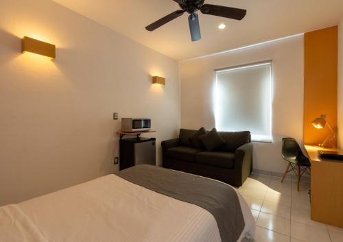 a bedroom with a bed and a couch and a ceiling fan at Hotel México Inn Express in Salamanca
