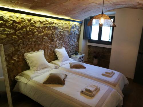a bedroom with two beds and a stone wall at Can Puig de la Pera in La Pera