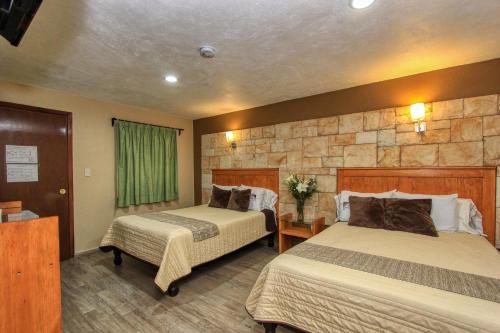 a hotel room with two beds and a stone wall at Hotel Mansion del Cantador in Guanajuato