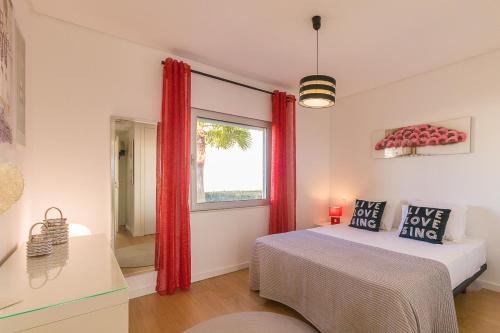 een slaapkamer met een bed en een raam met rode gordijnen bij Casa Migui Design Villas By ALzira in Albufeira