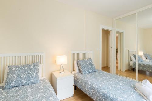 sypialnia z dwoma łóżkami i lustrem w obiekcie Alferez II by ELE Apartments w Maladze