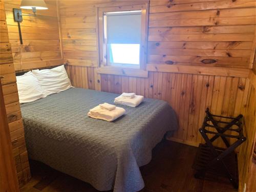 a bedroom with a bed with two towels on it at Pine Crest Motel & Cabins in Barton