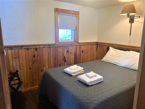 a bedroom with a bed with two towels on it at Pine Crest Motel & Cabins in Barton