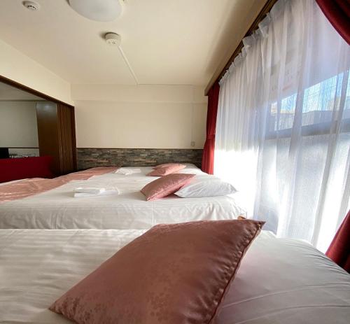 two beds in a hotel room with a window at Laforet Tokaichi / Vacation STAY 75082 in Hiroshima