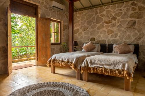 a bedroom with two beds and a stone wall at Villa Sunset Jogjakarta in Yogyakarta