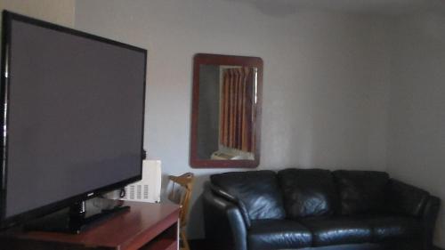 a living room with a black leather couch and a flat screen tv at Laurel Inn in Oakland