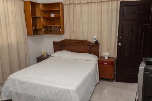 una camera da letto con un letto con lenzuola bianche e un armadio di Apartamento amoblado a Quibdó