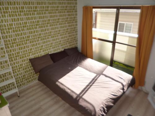 a small bed in a room with a window at THE MICKEY CARLTON Ohashi 206 in Shiobaru