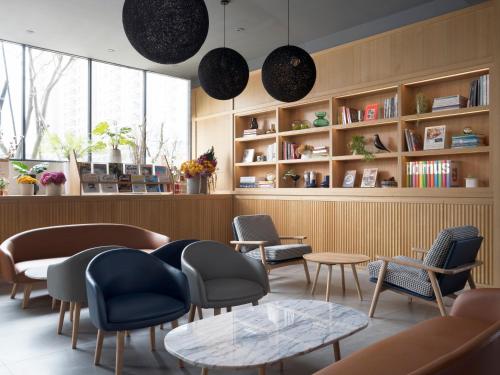 a waiting room with chairs and tables and bookshelves at Kindness Day Hotel in Tainan