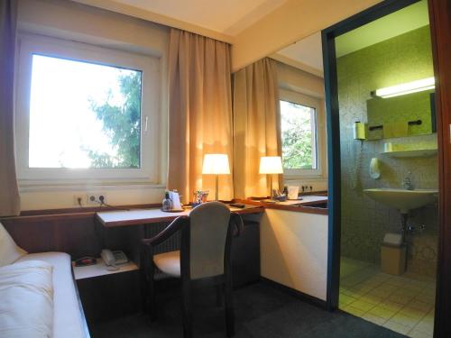 a hotel room with a desk and a sink at Hotel Katharinenhof STANDARD in Dornbirn