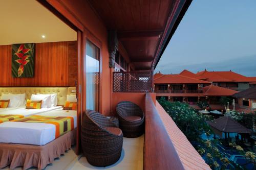 a hotel room with a balcony with a bed and two chairs at Wina Holiday Villa Kuta Bali in Kuta
