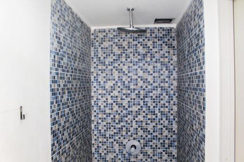 a bathroom with a shower with blue tiles at Minimalist and Stylish Studio No Kitchen Apartment at Aeropolis Residence By Travelio in Tangerang